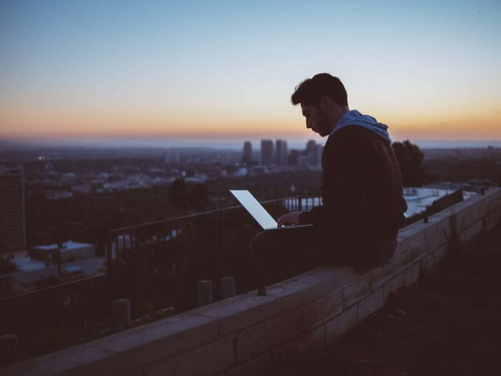 mann mit laptop auf brücke